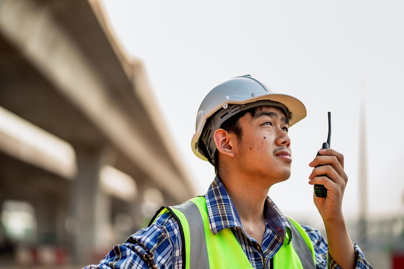 Werknemer met helm op een werf bekijkt zijn smartphone